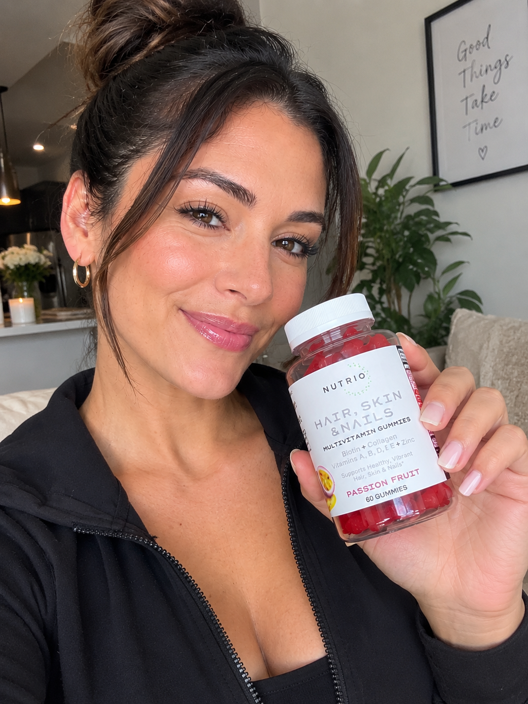 Woman at home holding NUTRIO Hair, Skin & Nails Multivitamin Gummies, Passion Fruit, 60 gummies